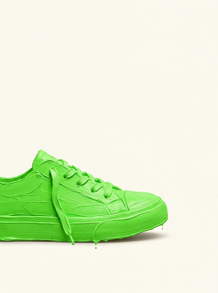 Neon-grüner Schuh in Impasto-Technik auf cremefarbenem Papier — Symbol für den ersten Schritt